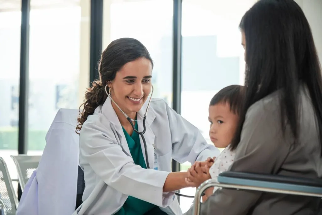 Médica que realizou a pós-graduação em Saúde da Família atendendo uma mãe com filho